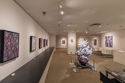 ギャラリーでの展示風景。壁に並ぶ絵画と、白とマゼンタの彫刻